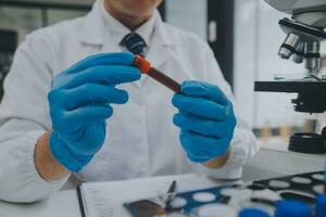 Scientist or medical in lab coat working in biotechnological laboratory, Microscope equipment for research with mixing reagents in glass flask in clinical laboratory. photo