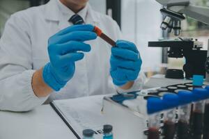 Scientist or medical in lab coat working in biotechnological laboratory, Microscope equipment for research with mixing reagents in glass flask in clinical laboratory. photo