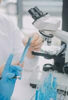 Scientist or medical in lab coat working in biotechnological laboratory, Microscope equipment for research with mixing reagents in glass flask in clinical laboratory. photo