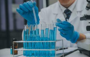 Scientist or medical in lab coat working in biotechnological laboratory, Microscope equipment for research with mixing reagents in glass flask in clinical laboratory. photo