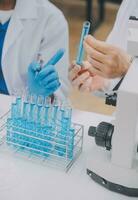 Scientist or medical in lab coat working in biotechnological laboratory, Microscope equipment for research with mixing reagents in glass flask in clinical laboratory. photo