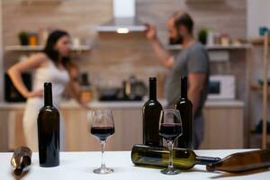 Close up of bottles and glasses filled with wine, liquor, booze and alcoholic beverage for alcohol addicts in background chatting. Intoxicated drunk people with unhealthy addiction photo