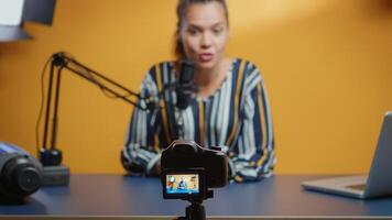 Selective focus on camera while social media star records an new podcast episode in her professional studio. Content creator new media influencer recording for internet web online subscribers audience photo