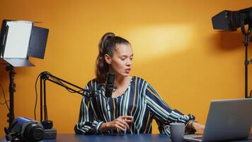 New media star talking to the camera and recording a new episode of her show. Content creator influencer on social media recording for internet web online subscribers audience new podcast with microphone in professional studio photo