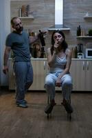 Depressed wife dealing with physical trauma and domestic violence smoking cigarette while listening to aggressive violent husband holding bottle of alcohol. Couple with social problems photo