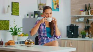 alegre ama de casa Bebiendo aromático té a desayuno. mujer teniendo un genial Mañana Bebiendo sabroso natural herbario té sentado en el cocina sonriente y participación taza para té disfrutando con agradable recuerdos. foto