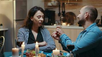 hermoso joven hombre preguntando para matrimonio su novia. hombre haciendo propuesta a su novia novia a ser en el cocina durante romántico cena. contento sorprendido mujer sonriente siendo sin habla. foto