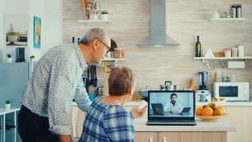 Senior woman during video conference with doctor showing pills bottle. Online health consultation for elderly people drugs ilness advice on symptoms, physician telemedicine webcam. Medical care internet chat photo