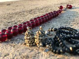 a red and black bead necklace laying on the ground photo