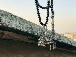 a necklace with two black beads and a silver bell hanging from a rope photo
