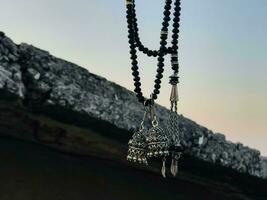 a necklace with two beads hanging from a rock photo