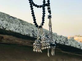 a necklace with two black beads and a silver bell hanging from a rope photo