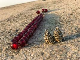 a red and black bead necklace laying on the ground photo