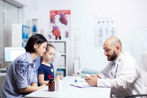 Doctor talking about diagnositc and treatment with mother of child in hospital office. Healthcare physician specialist in medicine providing health care services treatment examination. photo