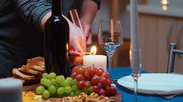 mayor mujer Encendiendo el vela esperando su marido para un romántico cena. mayor antiguo esposa preparando festivo comida con saludable comida para aniversario celebracion, sentado cerca el mesa en cocina. foto