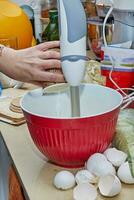 Homemaker Whisking Pancake Batter in Kitchen with Blender and Bowl photo