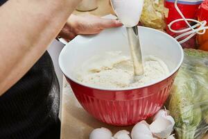 Homemaker Whisking Pancake Batter in Kitchen with Blender and Bowl photo