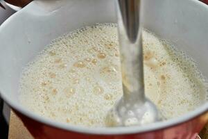 Homemaker Whisking Pancake Batter in Kitchen with Blender and Bowl photo