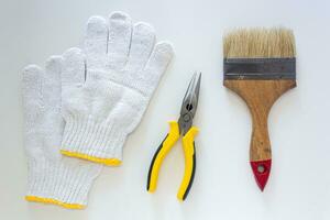 hogar mejora y mantenimiento básico herramientas, guantes , alicates y Cepillo de pintura en blanco antecedentes. foto