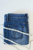 Fashion of blue jeans with measurement tape on white background with copy space. photo