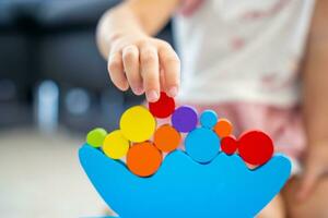 Little girl playing with wooden balancing toy on the floor in home living room. Focus on balancer photo