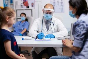 Specialist doctor wearing protective mask and gloves against covid19 writing medical expertise. Healthcare practitioner in medicine providing professional radiographic treatment in hospital clinic photo