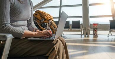 Young Asian woman using laptop to check flight times in airport for vacation photo