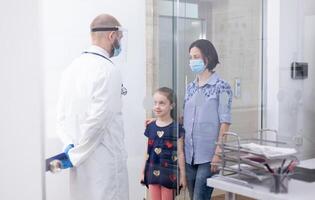 Pediatrician wearing face mask against coronavirus during consultation of child. Physician, specialist in medicine with protection mask providing health services, consultation. photo