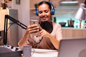 Famous influencer reading messages from fans on her phone during live on her social media. Creative online show On-air production internet broadcast host streaming live content. photo