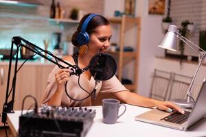 Vlogger speaking with follower on live using professional microphone wearing headphones. Creative online show On-air production internet broadcast host streaming live content and recording photo