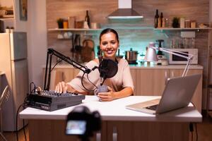 Person speaking about her life during podcast in home studio with neon light behind her. Creative online show On-air production internet broadcast host streaming live content. photo