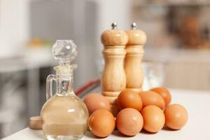 Pastry ingredients for homemade cakes and bread in empty kitchen. Modern dining room equipped with utensils ready for cooking with wheat flour in glass bowl and fresh eggs on table photo