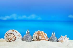 blanco conchas marinas con Navidad árbol plata brillante pelotas en el arena de el playa en soleado día con el mar. nuevo año, fiesta en caliente países. Copiar espacio foto