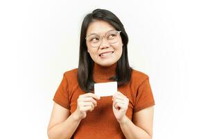 sosteniendo una tarjeta bancaria en blanco o una tarjeta de crédito de una hermosa mujer asiática aislada de fondo blanco foto