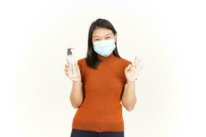 vistiendo médico máscara y participación mano desinfectante de hermosa asiático mujer aislado en blanco foto