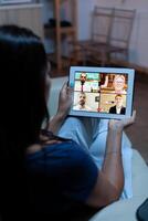 Back view of woman on videocall sitting on comfortable couch. Remote worker having online meeting consulting with colleagues on video conference and webcam chat using internet technology. photo