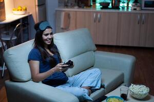 jugador utilizando palanca de mando jugando vídeo juegos en consola sentado en sofá en vivo habitación. emocionado determinado mujer utilizando controlador gamepad teclado estación de juegos juego de azar y teniendo divertido victorioso electrónico juego foto