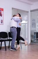 Excited husband hugging wife after receiving good news from doctor in hospital waiting area. Happy young couple for good clinical result screaming in reception area photo