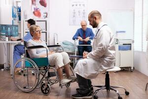 Elderly woman in wheelchair at doctor appointment in recovery clinic. Man with disabilities ,walking frame sitting in hospital bed. Health care system, clinic patients. photo