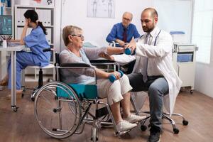 Medical therapist helping disabled senior woman with physiotherapy. Elderly invalid patients in hospital following rehabilitation treatment with help from medical personal. photo