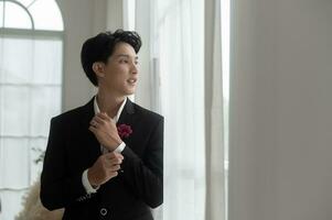 Portrait of young handsome groom in suit, preparing for wedding ceremony photo