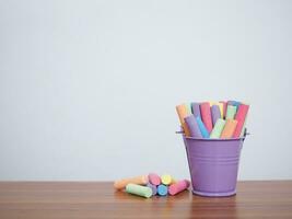 Multicolor chalk on wooden table for education background photo