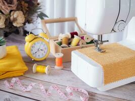 Close up sewing machine working with yellow fabric, sewing accessories on the table, stitch new clothing. photo
