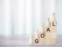 Wooden human figure and wooden blocks with the word GOAL, The concept of business strategy for success and winner concept photo