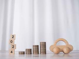 Wooden block with number 2024, stack of coins and toy car. The concept of saving money for car loan, insurance, paying tax in new year 2024 photo