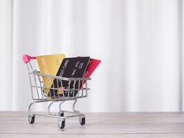 Credit cards in shopping cart on the table with white curtain background. photo