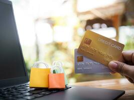 Woman hand holding credit cards and shopping bags on a laptop keyboard. Concepts about online shopping that offers home delivery photo