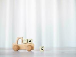 Wooden toy car and Wooden blocks with the word TAX . The concept for paying TAX for car in future photo