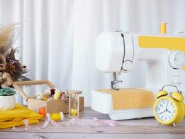 de coser máquina trabajando con amarillo tela, de coser accesorios en el mesa, puntada nuevo ropa. foto