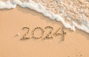 2024 año escrito en el playa en el puesta de sol tiempo. nuevo año 2024 concepto foto